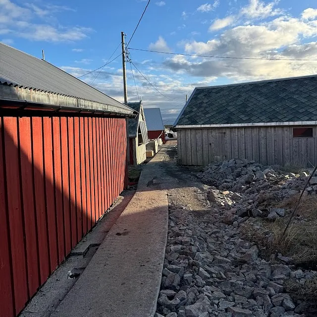 Oppgradering av smal gangvei mellom tradisjonelle naust med ny kantstein og steinsetting langs traséen.