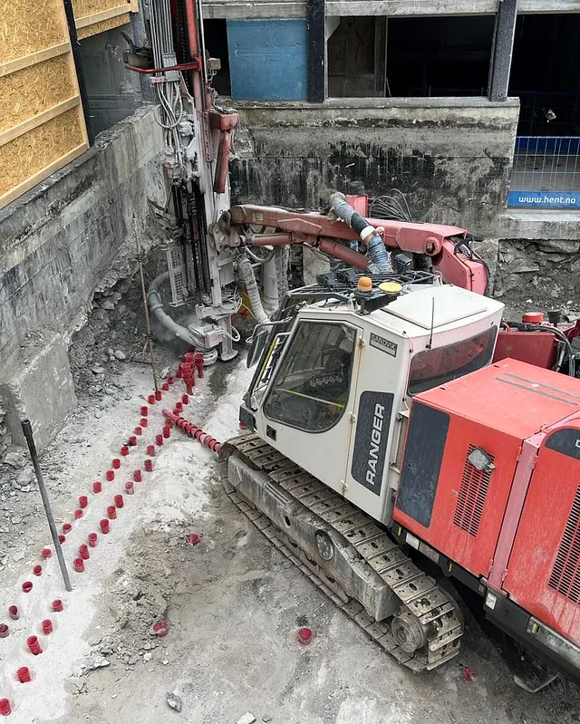 Borerigg i bruk for grunnstabilisering ved byggegrop, med markering av borepunkter.