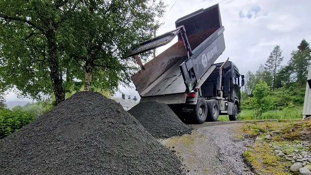 Lastebil tipper masse med grus på bakken