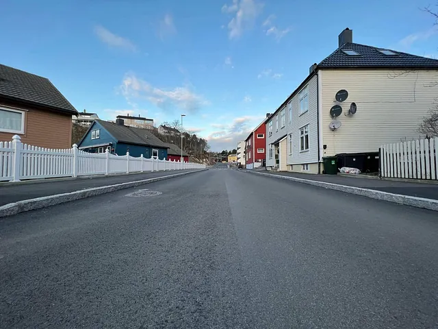 Nyasfaltert gate i boligområde er ferdigstilt med nye fortau og kantstein – et tydelig tegn på ferdigstilt infrastrukturarbeid.