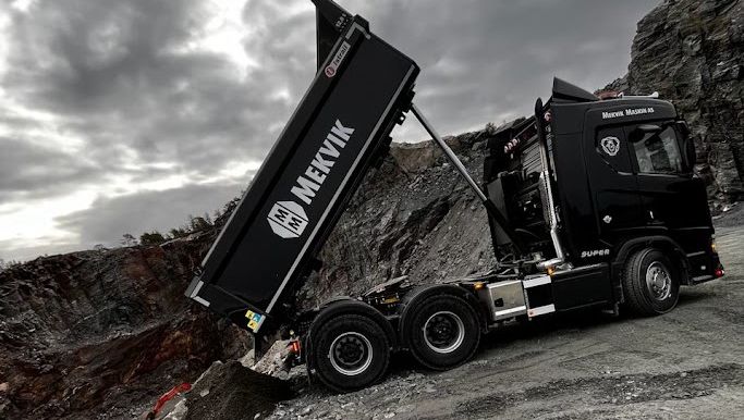 Lastebil tipper masse med grus på bakken