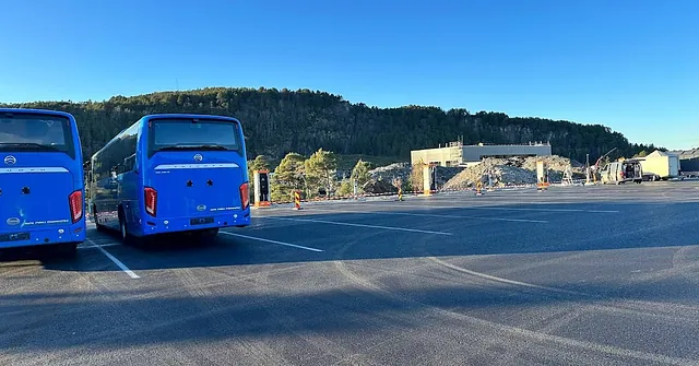 To busser parkert på bussdepot med flere parkeringsplasser